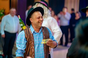 Guests wearing casual attire and hats enjoying a lively celebration indoors.