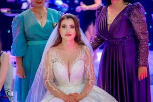 Wedding party gathering featuring elegant dresses in jewel tones and white under dramatic lighting.