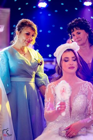 Wedding celebration with guests in turquoise and white dresses under blue mood lighting and twinkling lights.