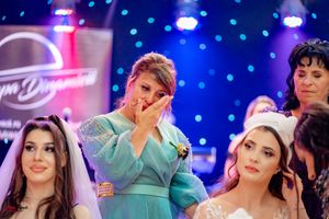 Wedding reception scene with blue lighting showing guests in turquoise dresses mingling.