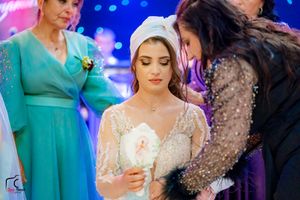 Wedding celebration scene with blue lighting and guests in formal attire at an indoor venue.