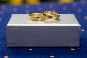 Gold wedding bands arranged artistically on white surface with blue dotted backdrop.