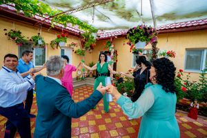 People dancing and celebrating at an outdoor patio with yellow walls and hanging plants.