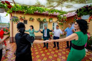 Group dancing in formation on a tiled patio with vine-covered walls and Spanish-style architecture.