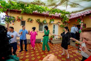 Wedding guests dancing in a line on outdoor terrace decorated with hanging plants.