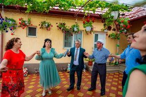 Festive group dance on tiled patio with decorative climbing plants and yellow walls.