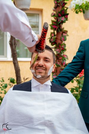 Barber giving a traditional straight razor shave during an outdoor event.
