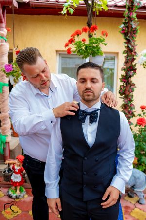 Formal gathering in garden setting with climbing roses and decorative elements.