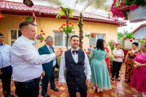 Wedding party members in formal attire mingle during an outdoor celebration with colorful garden decor.