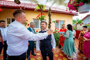 Garden wedding celebration with guests in formal attire mingling near a yellow stucco building.