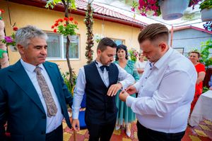 Social interaction during an outdoor celebration with floral decorations and yellow building backdrop.