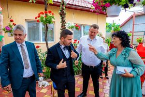 Animated discussion during outdoor celebration with hanging flower baskets and yellow walls.
