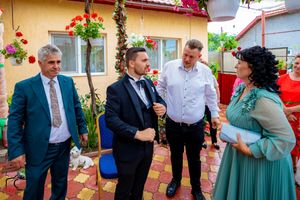 Lively conversation at an outdoor party with decorative flowers and red tile flooring.