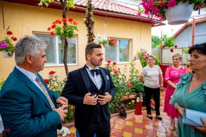 Outdoor celebration with formal dress under flowering vines and decorative garden elements.