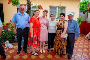 Group photo of party guests standing together on decorative tiles with floral backdrop.