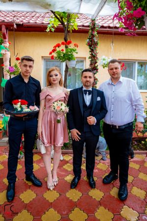 Formal group photo against yellow building with red geraniums and decorative tile flooring.