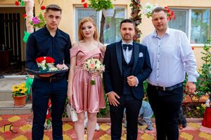 Line of people posing for photos on patterned tiles with floral decorations.
