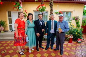 Large group photo on decorative patio with yellow walls and hanging flower baskets.