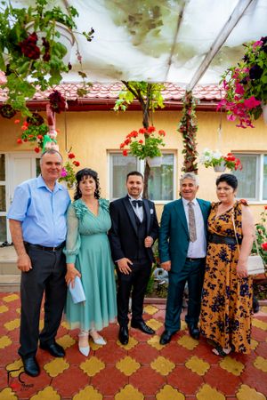 Group photo with varied attire against yellow wall and decorative garden setting.