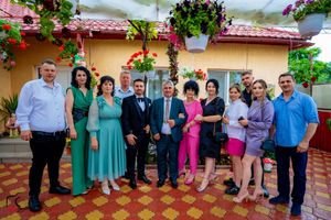 Panoramic shot of wedding guests lined up against a yellow stucco wall with flowering vines.
