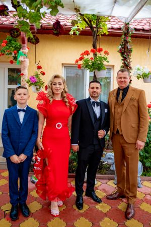 Wedding party members in formal attire posing on tiled patio with flowering backdrop.