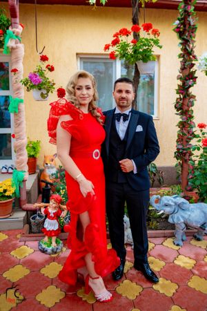Couple in red dress and navy suit dancing on decorative outdoor patio.