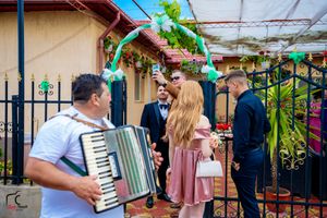 A group of wedding guests gather under a covered patio area with decorative green garlands.