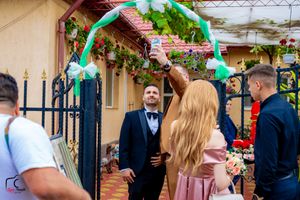 People celebrate at an outdoor wedding reception with green decorations and string lights.