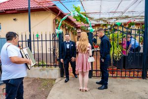 Wedding guests mingle under a covered outdoor venue with red roof and decorative elements.
