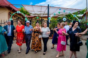 Wedding guests dance and celebrate in a line at an outdoor reception venue.