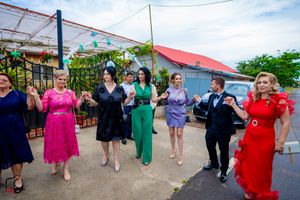 Wedding guests perform a group dance at an outdoor venue with red roof.