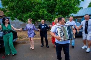 Group dancing outdoors with accordion player providing music during festivities.
