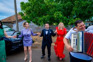 Celebration with accordion player and dancers in formal wear on a street.