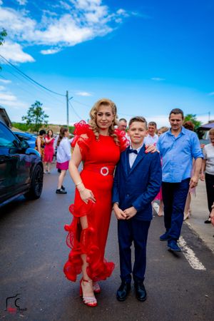 Formal celebration outdoors with guests in elegant attire posing on street.