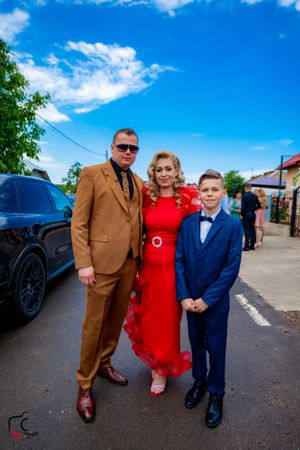 Family in coordinated formal wear poses together during outdoor celebration.