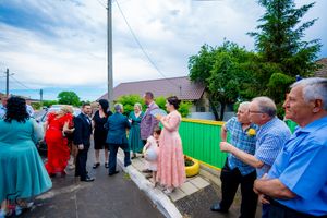 A group of people stand together at an outdoor event with a green fence in the background.