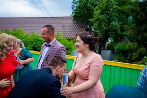 Attendees mingle at an outdoor social gathering with a green fence visible.