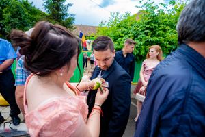 Wedding guests gather outdoors in formal attire on a sunny day during a celebration.
