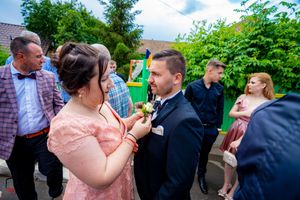 Wedding party members mingle in a garden setting under blue skies.