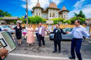 Wedding party gathers outside an architectural building with turrets on a beautiful day.