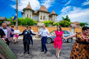 Wedding guests socialize on a paved area outside a building with distinctive towers.