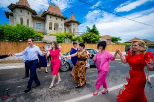 Wedding celebration with guests dancing and mingling outside a turreted building.
