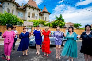 Dancers performing a synchronized line dance in bright colored outfits on a sunny street.