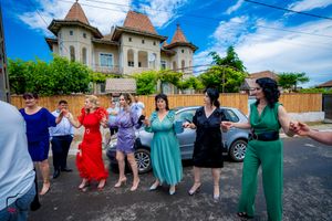 Group performing traditional dance moves in vibrant attire outside historic buildings.