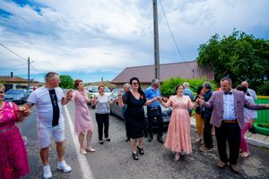 People joined together in a traditional dance line against a bright blue sky.