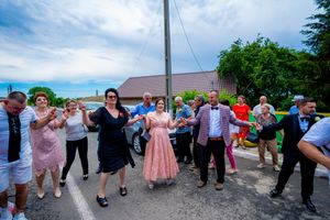 Festive outdoor dance gathering with people linked together in front of historic buildings.
