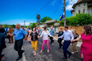 Participants linked together performing a festive circle dance outside a historic building.