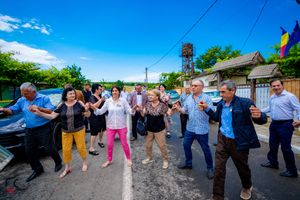 A panoramic view of people performing a traditional dance in a line formation on a summer day.
