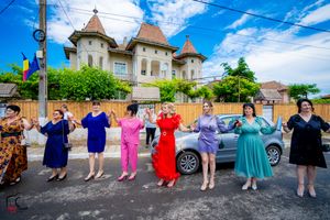 Colorfully dressed dancers performing a traditional line dance outside a turreted building.