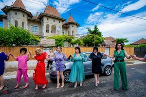 People in vibrant dresses and formal wear dancing in formation during an outdoor celebration.